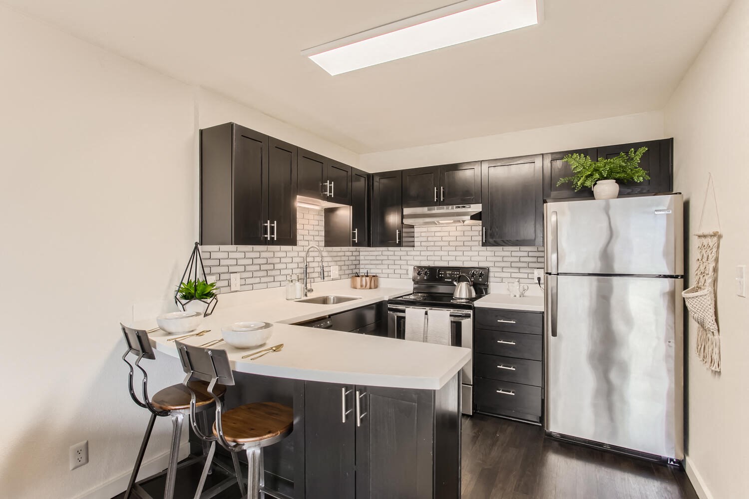 Downtown Portland, OR, Urban Apartments - Linc 301 - Kitchen with Stainless Steel Appliances, Black and Modern Cabinets, Corian Countertops, and High Chairs.